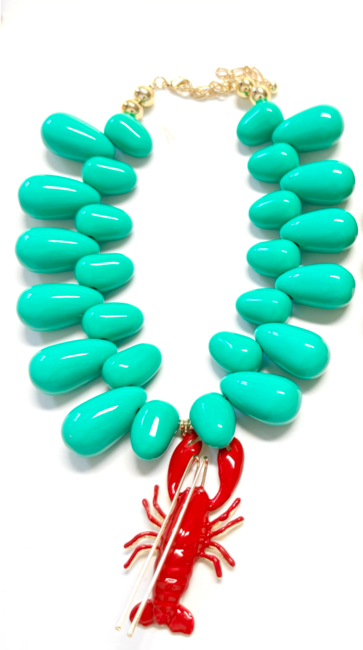 Turquoise necklace with a red lobster charm on a white background