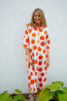 Woman wearing a white dress with orange fruit pattern against a white background