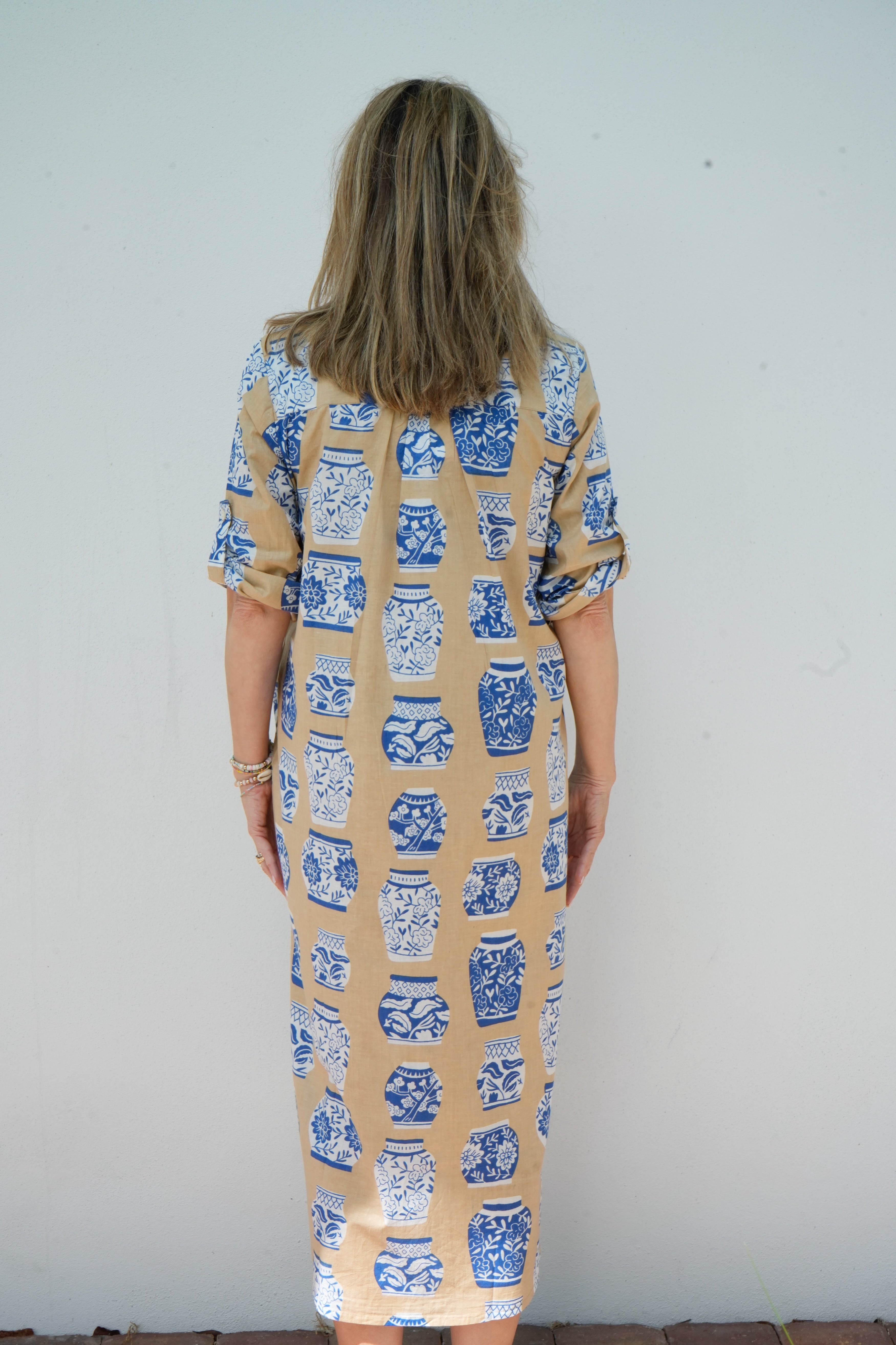 Woman wearing a patterned dress with blue and white designs on a plain background