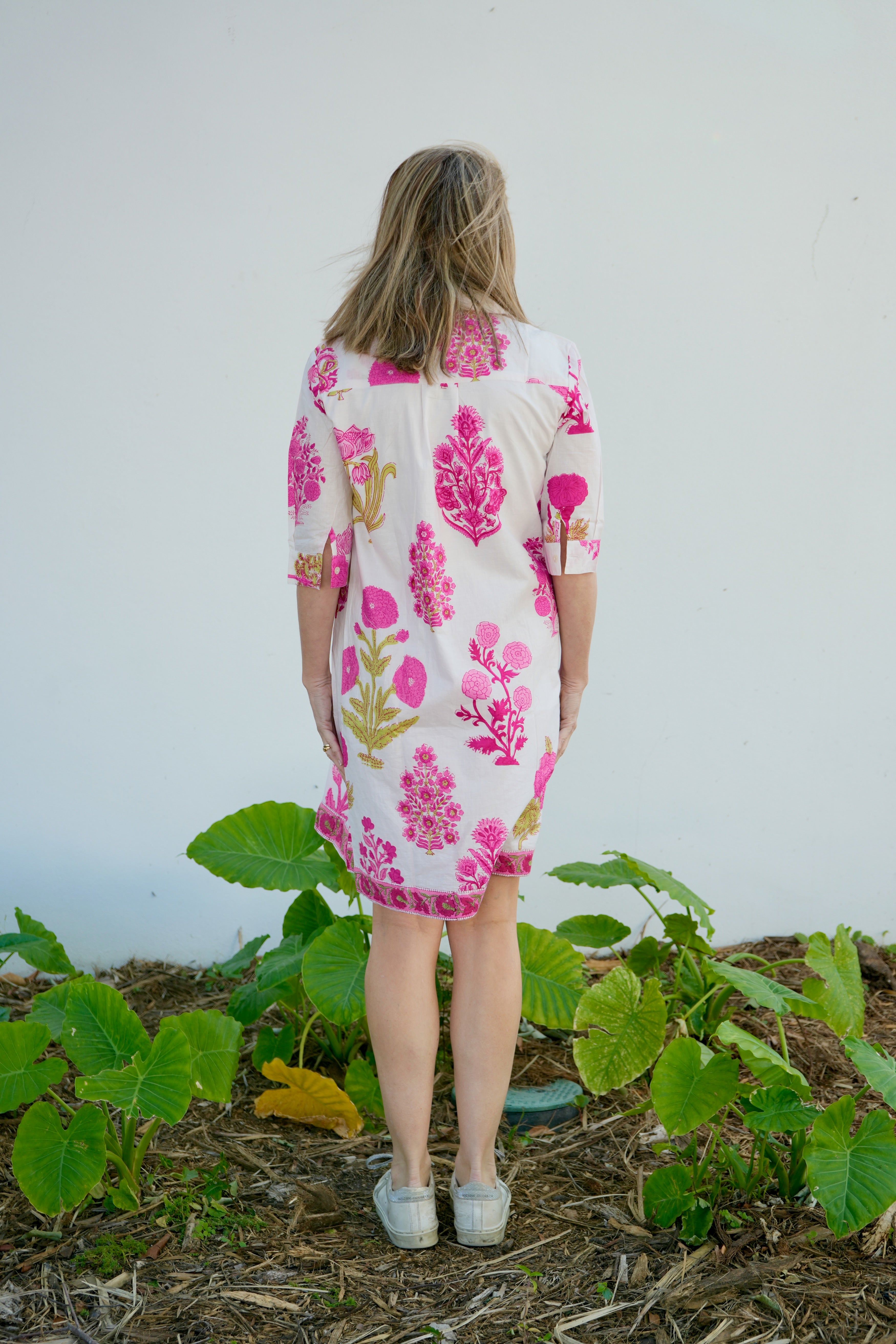 Person wearing a floral dress standing in a garden