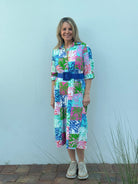 Woman wearing a colorful dress with a blue belt against a light gray background
