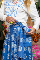 Person wearing a white sweatshirt with 'BEACH BUM' text and blue ginger jar patterned skirt.